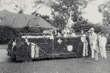 Auto geschmückt als 1. Augustwagen mit Personen. Auf dem Rücksitz, Anna Suter-Bischofberger, in Berner Tracht. Sumatra, 1. August 1931. © Schweizerisches Nationalmuseum